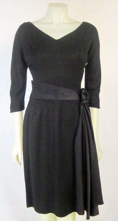 Elegant Black Dress from the early 1960s Mad Men Era. It has ha gorgeous black satin waist rosette side sash. Metal Zipper and 3/4 length sleeves! 

Bust: 34
