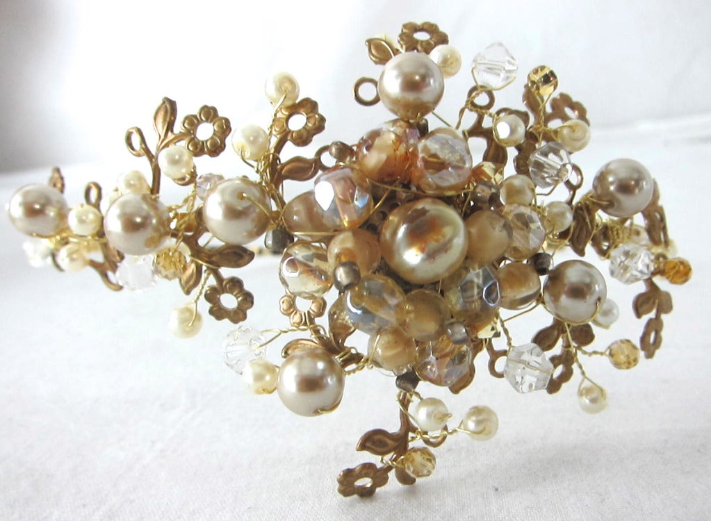 Gorgeous hand wired headband made of gold tone metal flowers , faux pearls and clear drops . Stunning! 

The arrangement: 4