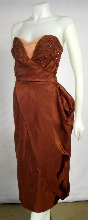 This is a gorgeous and RARE strapless copper taffeta cocktail dress. The bust is soutache, bugle beads  and faux pearls with ruche blush modesty panel and boning . It has an interesting  side sash and side metal zipper . STUNNING!

BUST:
