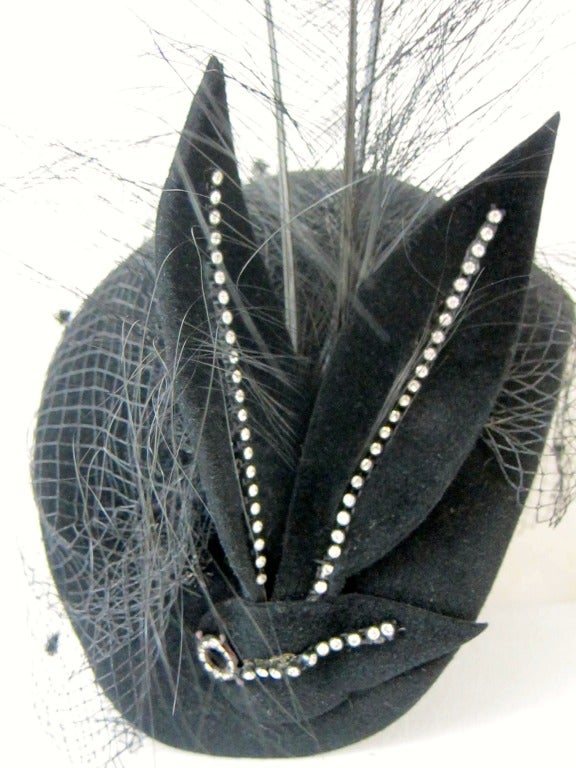 Great hat!   1920s style black Cloche with Huge feather, rhinestones  and  black veil. The veil has little shiny spurs 
Fits  a 22