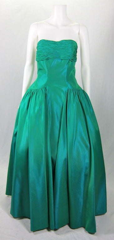 This is a gorgeous blue green iridescent strapless evening gown with matching bolero that has ruching at the sleeves.
The bodice is ruched with boning in the front and back. It has a side metal zipper. The skirt is lovely with that wonderful