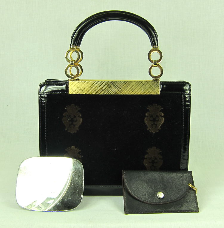 Fantastic handbag from Buenos Aires from the late 1950's! It has a wonderful shape. Both sides are velvet with deep gold emblems. The bottom and sides are trimmed in patent leather. The leather  handles have round gold tone disks. The interior has