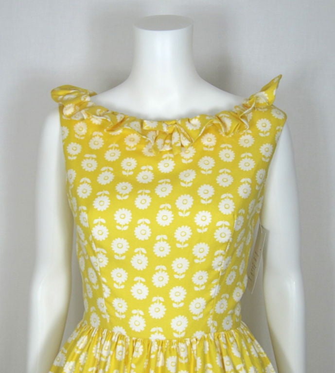 Featured is a summer-ready Lanz Original dress with a 1962 copyright label. The fabric looks like a cotton piqué, medium weight with a woven texture and slight sheen. The print is a white daisy silhouette motif against a warm yellow background. The