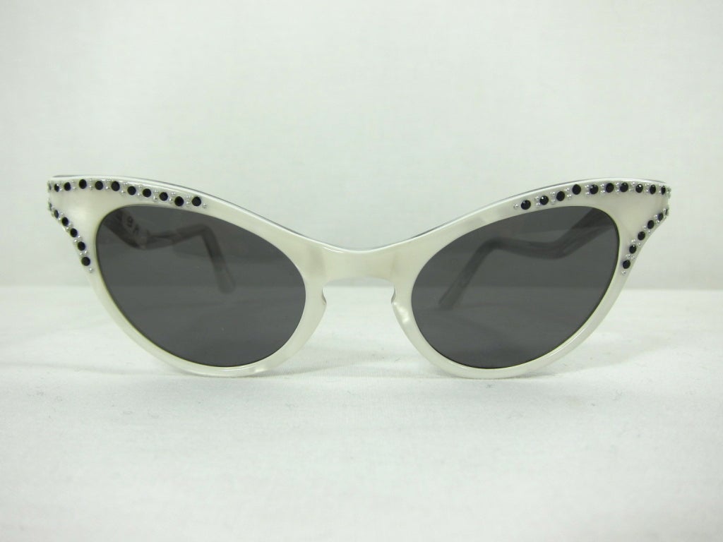 Vintage 1940- 1950 white lucite embellished with silver studs and black rhinestones french bend temples. <br />
Acquired from a family owned eye glass company that started designing in the 1930's.<br />
<br />
Front width: 5 1/8