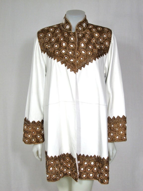 This is a  FANTASTIC  soft white leather swing coat that is heavily beaded in gold bugle beads and gold shinier  beads that form the out line of  circles around the cut outs of the leather and also used along the neckline , hem and cuff. 
The maker