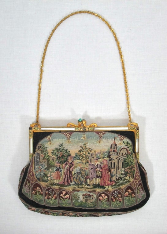 Featured is a lovely vintage needlepoint purse from the 1930s-1940s. The gold tone frame is accented with enameled flowers, Lucite and faux jewels at the clasp. Short chain strap and silk lining with 2 pockets. Excellent condition with the exception