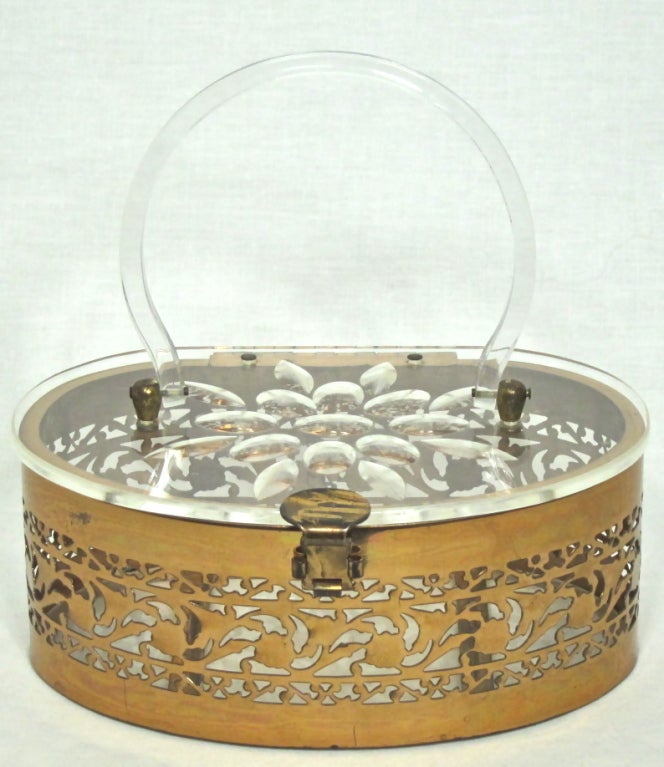 Featured is an elegant vintage purse from the 1950s. The body is made of brass with a pierced floral design all around. Lucite top, bottom and handle, with carved lid. Strong clasp.

Height: 8