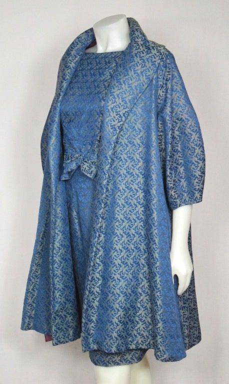 Featured is a gorgeous cocktail dress and coat set from the late 1950s-early 1960s, by Molly Modes of New York. Fabulous deep blue brocade with abstract woven design. Blouson front bodice with large bow. Straight skirt with back kick pleat. Unlined