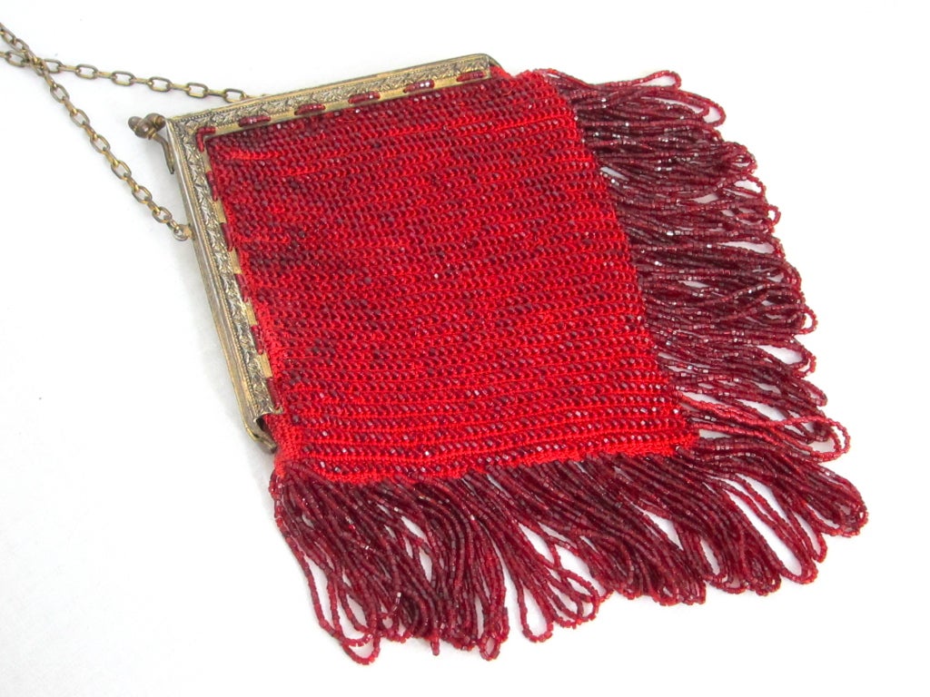 Featured is a ruby red vintage beaded purse from the 1920s. Ornate gold tone frame, chain strap, kiss lock closure. Red glass seed beads with looped fringe. Faded red fabric lining.

10