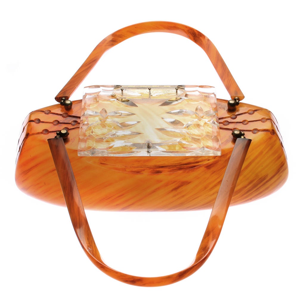This is a great looking large bakelite hand bag with a carved design on the side as well as a clear carved lucite lid.  It is signed on the inside brass closure. <br />
<br />
*Measurements*<br />
11 1/4