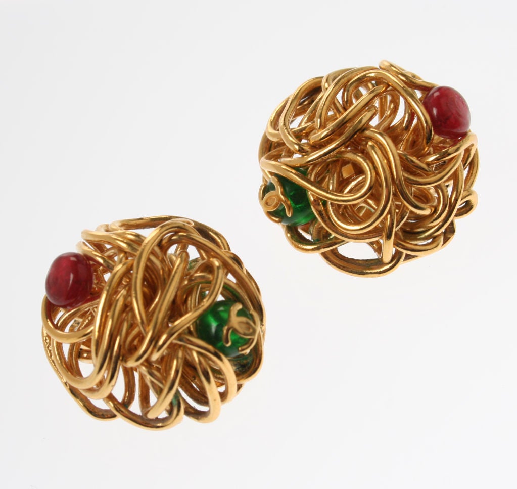 These are very modern and sculptural gilt wire earrings with red and green poured glass. The CHANEL logo is affixed to the green glass cabachon and they are marked 97 P.
They are 1" in diameter.