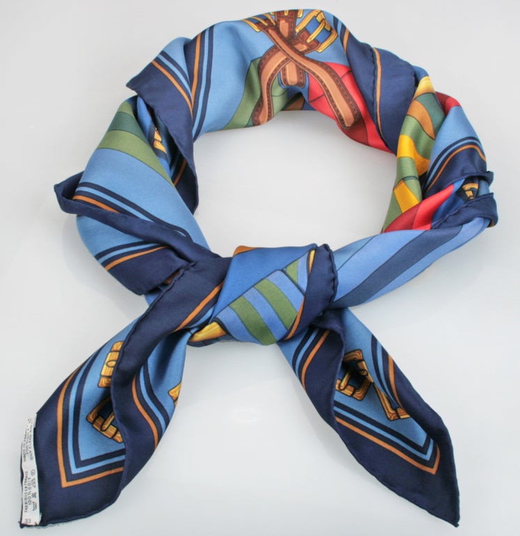 This is a graphic Hermes scarf featuring suspended cinch belts. The scarf ws designed by J Metz.