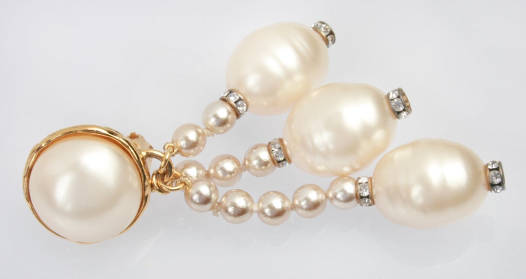 These are glamorous Chanel earrings.  Three strands of small pearls, each atop a single larger pearl, are accented by rondels of rhinestones to add a little sparkle.