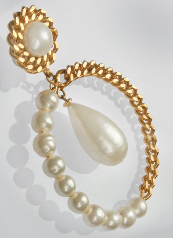 This is a  stunning combination of both elegance and youthful flair. Chanel combines faux pearls and heavy gold toned metal links in this pair of oversized hoop earrings.