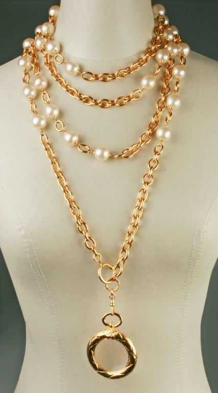 This is a fabulously long CHANEL necklace with faux pearls and gold tone chain. The necklace length is 88 inches in length. The magnifying glass is 2 inches in diameter and is removable from the chain.
Magnifying glass is marked Chanel, Made in