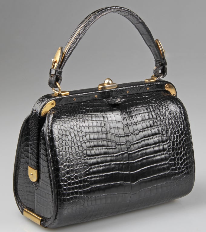 This  wonderful and stylish handbag has great hardware and a pocket watch. 
The handbag has one zippered compartment and one snap pocket with a pouch behind.
The bag itself is 7 inches high not including the strap