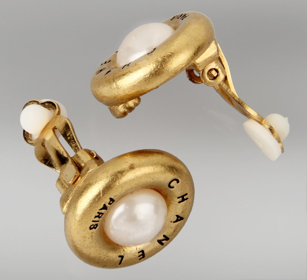 This is an  unusual smaller pair of CHANEL earrings with faux pearl and a rich gold toned metal. Chanel Paris is inscribed on the front.

Marked Chanel 93 A Made In France