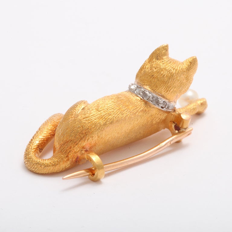 18kt gold cat brooch, with emerald eyes and diamond collar, playing with a pearl ball.