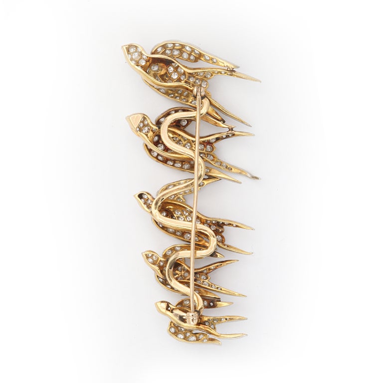American antique bird brooch: flock of swallows flying in formation.  Approximately 8 carats of diamonds mounted in platinum and gold. Length: 3 in.
