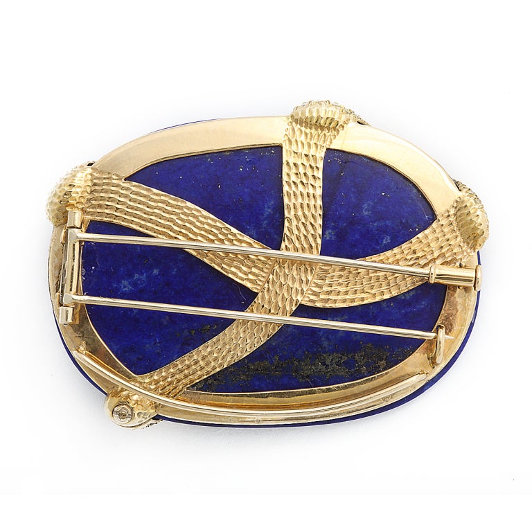 Oval lapis lazuli brooch mounted with fancy, intense yellow diamond snake with cabochon ruby eyes.
Length: 2-1/2 inches; width: 2 inches