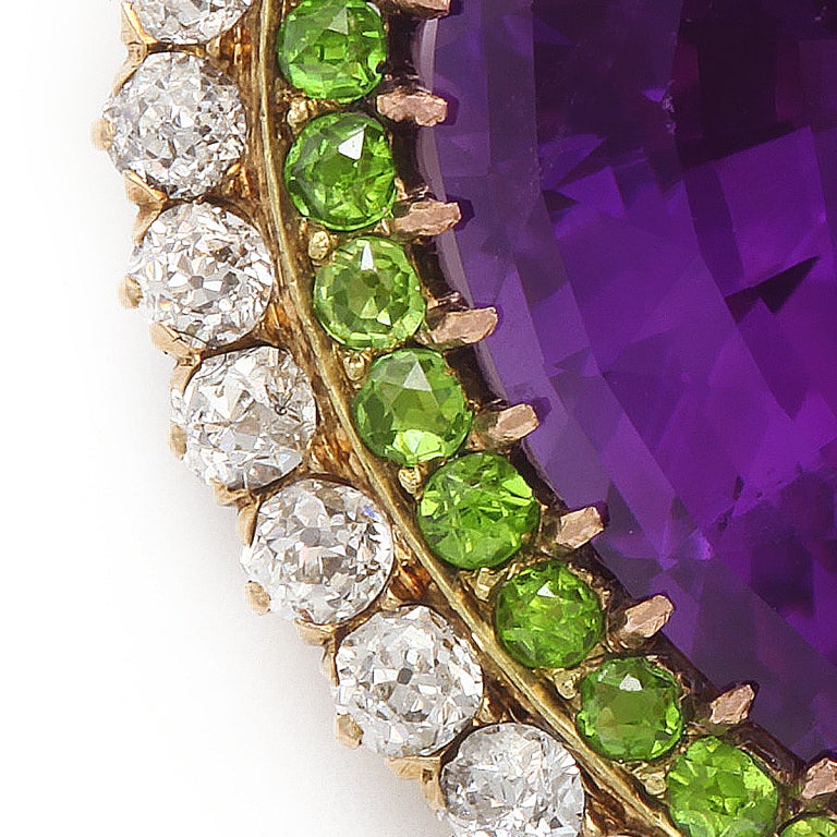 Amethyst, diamond, and demantoid garnet heart-shaped brooch,displaying the suffragette colors. Mounted in gold, this pin can also be worn as a pendant.