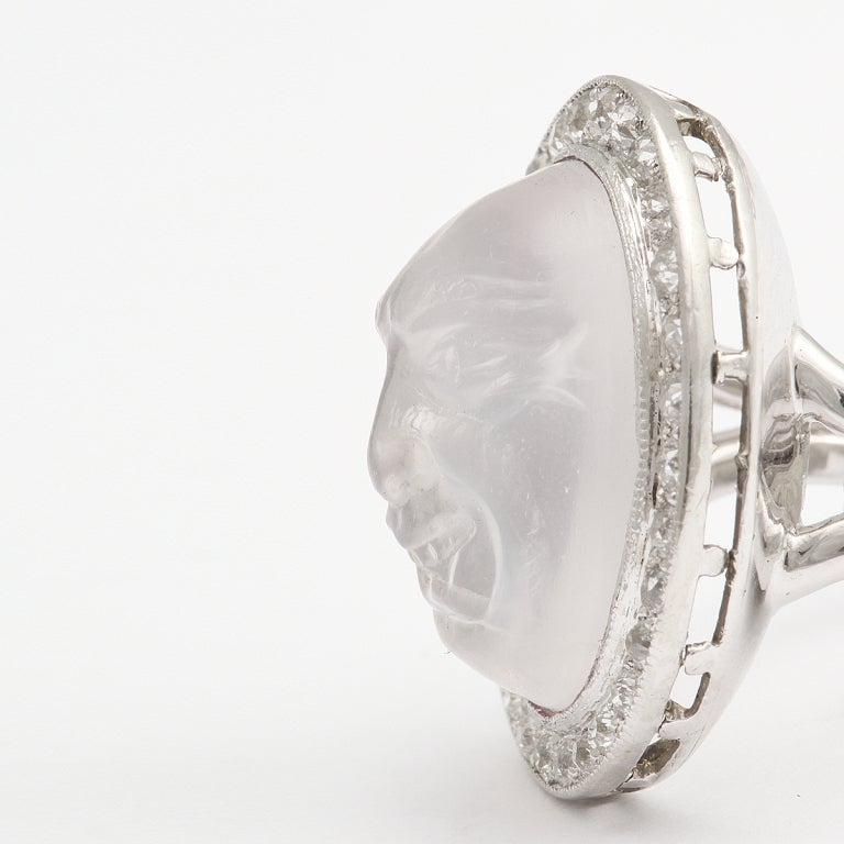 Carved moonstone ‘Man in the Moon’ diamond cluster ring, set in a platinum mount.