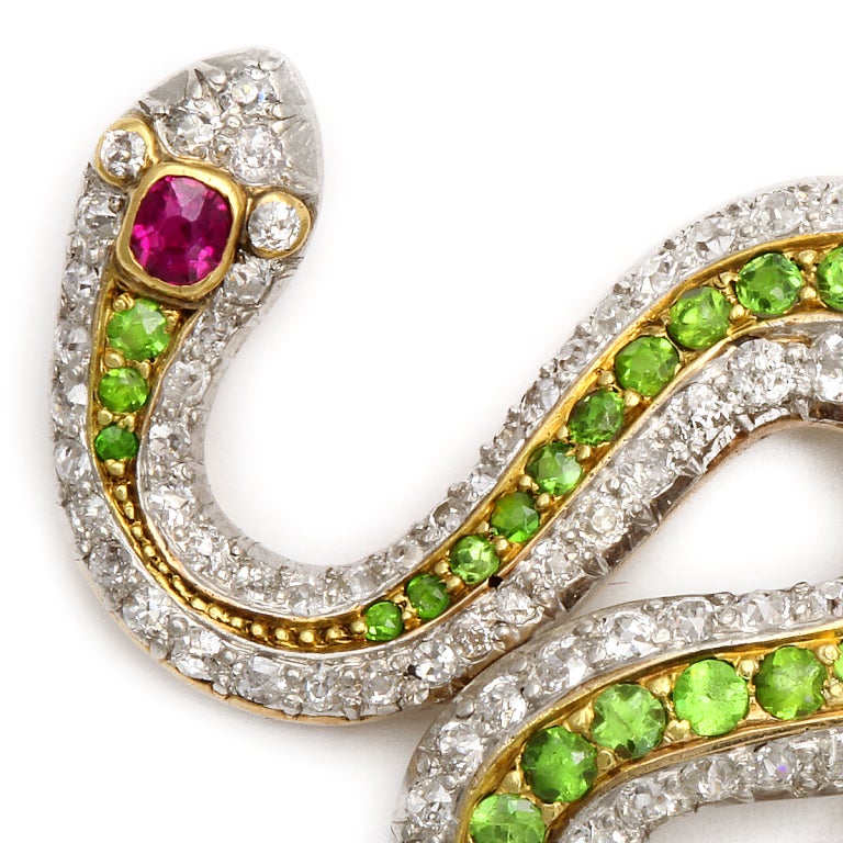 Diamond and green garnet slithering snake brooch, set in platinum and gold, and with a ruby-set head.