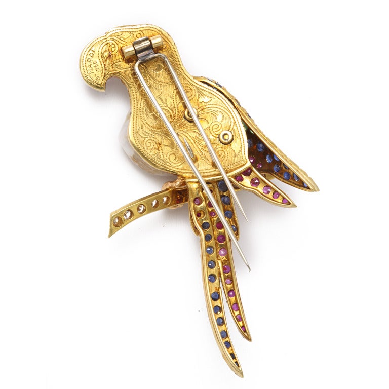 Gold-mounted brooch in the form of a Macaw with a baroque natural pearl best and multi gem feathers perched on a diamond branch.
By Nardi, a jewelry firm founded circa 1920 by Giulio Nardi who became highly regarded for his use of