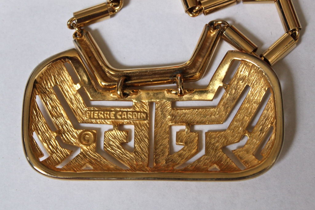 Very dramatic oversized gilt metal modernist necklace from Pierre Cardin dating to the 1960's. Pendant has a burnished gilt finish and is trimmed with high polished gilt metal. Chain has the same high polish finish as trim on pendant. The pendant
