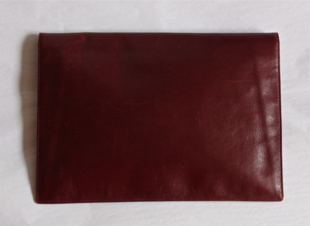 Rich burgundy leather clutch with gold hardware at corners from Gucci dating to the 1970's. Measures approximately 11.5