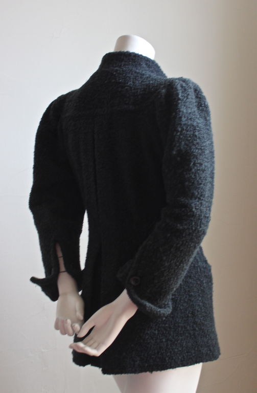 Very rare black boucle wool jacket from Ossie Clark for Quorum dating to the 1970s. Labeled a UK 8, which fits a US size 4-6. Pockets at hips. Attached belt. Fully lined. Buttons at waist   and French cuffs at wrists. Made in England. Very good