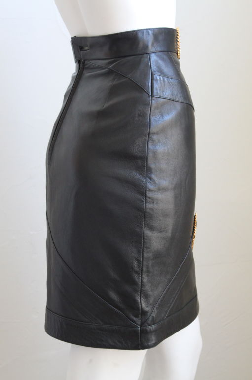 Luxurious black lambskin skirt with gilt hardware from Chanel dating to the 1980s. Skirt is labeled a French size 36 which best fits a US 2. The waist measures 24