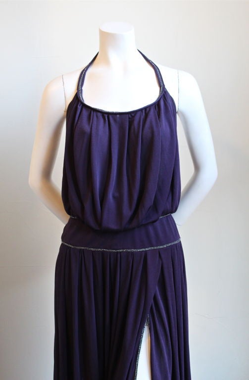 Purple viscose jersey gown with metallic silver toned trim and extra high thigh slit from Bill Gibb dating to the 1970's. Blouson bodice. Halter neckline with decorative button at back of neck. Dress fits a US 6. Made in England. Excellent condition.