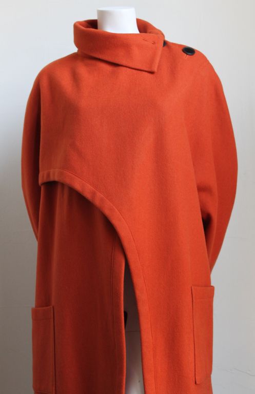 Pumpkin colored wool coat with cut-away from Yohji Yamamoto dating to the 1980's. Labeled a size medium although this coat fits a size 4-12 due to loose cut. Black plastic buttons at neck. Patch pockets at hips. Unlined. Made in Japan. Excellent