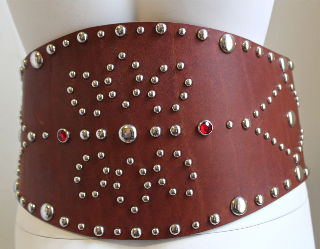 Very rare brown leather corset belt with silver studs from Ralph Lauren dating to the 1970's. Two red faceted glass stone accents at back. Gorgeous rich brown patina. Very thick leather. No size indicated, however belt comfortably fits a 28-31