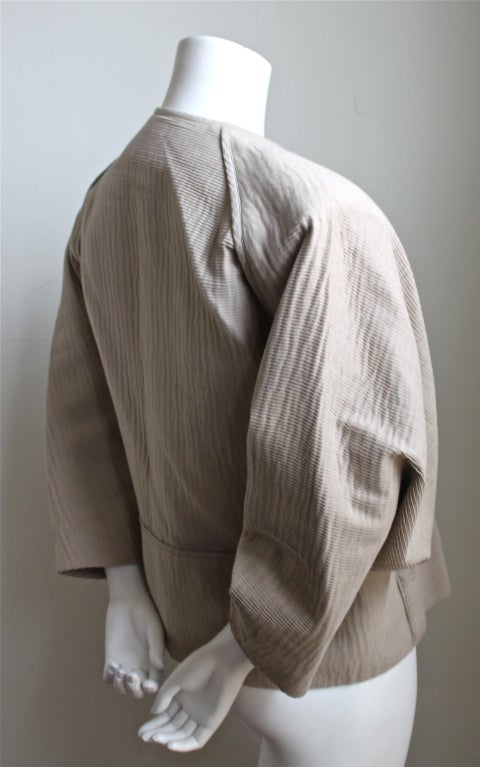 Very rare tan micro-pleated jacket with unique triangular button loops designed by Issey Miyake dating to the late 1970's. Labeled a size 's', although this jacket easily accommodates a size  medium or large due to voluminous cut. Pockets at hips.