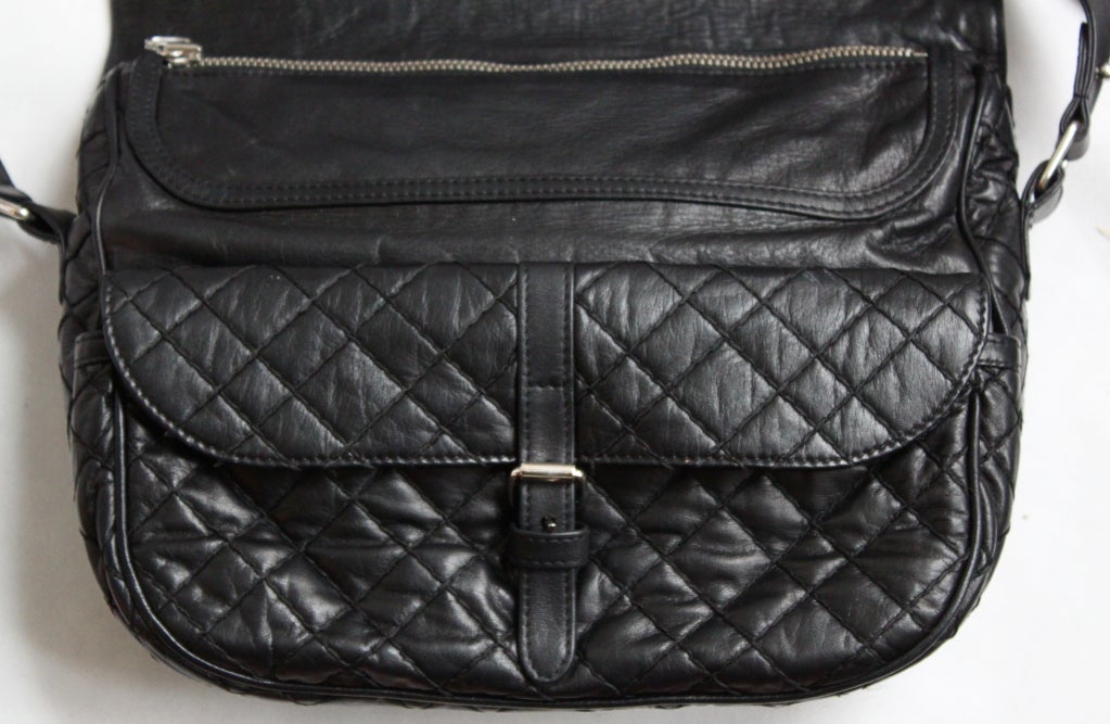 Jet black leather quilted shoulder bag designed by Christophe Decarnin for Balmain. Bag features: silver-tone hardware, black quilted top-stitch detailing, a fold-over front flap, a buckle and flap-fastening quilted pouch underneath flap, a zip