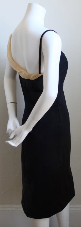 Very unique black corseted pencil dress with a cut away bustline that reveals a flounce of fleshy toned delicate silk chiffon from Gianni Versace couture dating to the 1990's. Dress best fits a size 6-8. Internal corset lining at bust. Zipper entry.