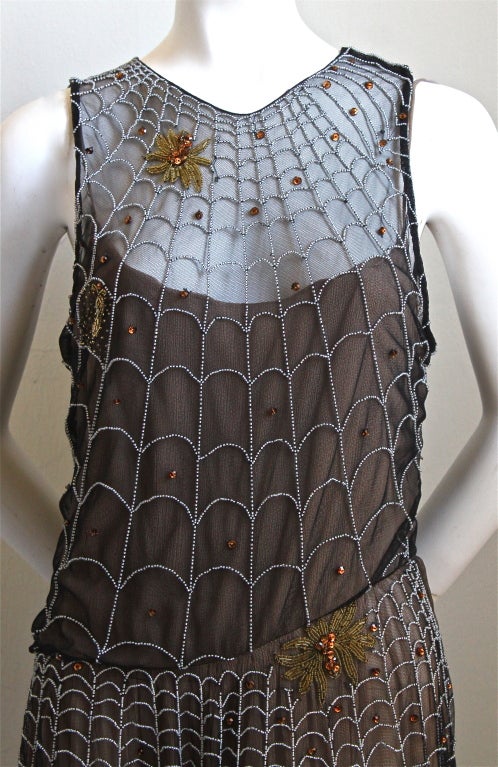 Very rare net dress with beaded spiders and a large web motif from Giorgio Armani dating to spring of 1990. Fits a size 6 or possibly an 8. Loose asymmetrical waistline. Fully lined in nude silk. Button and snap closure at side. Made in Italy.