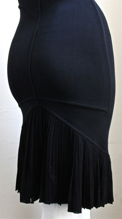 Jet black slinky knit dress with open neckline and pleated fishtail hemline from Azzedine Alaia dating to the 1990's. This dress best suits a medium, large or someone with broad shoulders. Dress measures approximately: bust 35