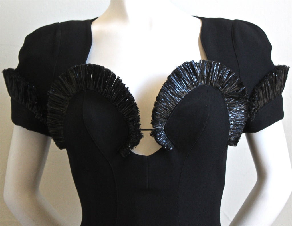 Very rare sculptured black dress with raffia trim designed by Thierry Mugler dating to the 1990's. Labeled a French size 38. Dress measures 34