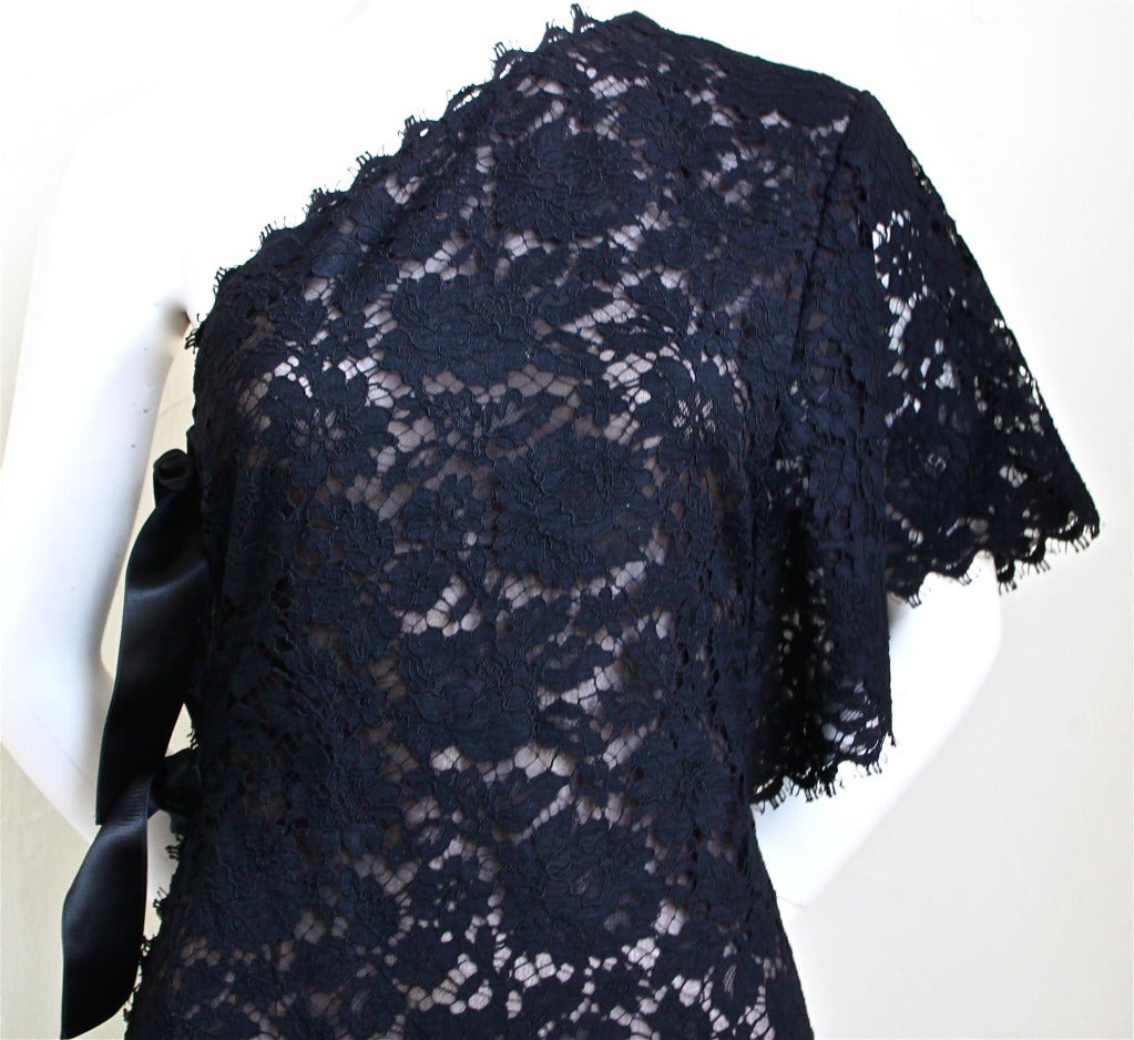Gorgeous jet black lace dress with asymmetrical sleeve and satin ties at side from Yves Saint Laurent rive gauche dating to the 1990's. Dress best fits a size 38. Measures approximately 33