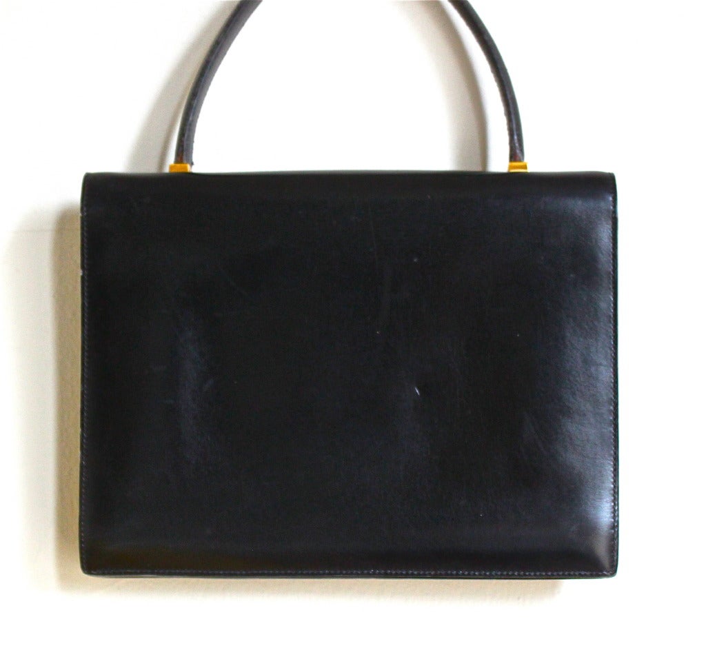 Jet black box leather top handle bag with gold hardware designed by Hermes dating to the 1960's. Bag measures 10.33