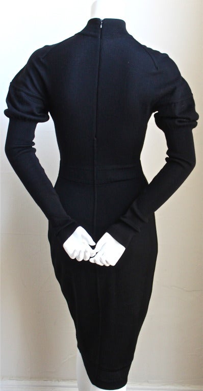 Jet black soft knit wool dress with mutton sleeves and decorative set in waist from Azzedine Alaia dating to the 1990's. Labeled a French size 'S'. Approximate measurements: shoulder 13-14