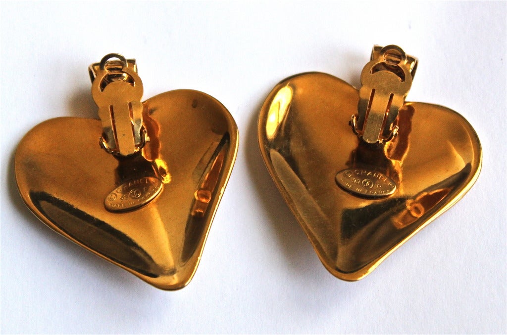 Oversized gilt metal heart earrings with 'CC' detail from Chanel dating to 1993. Clip backs. Approximately 2.25