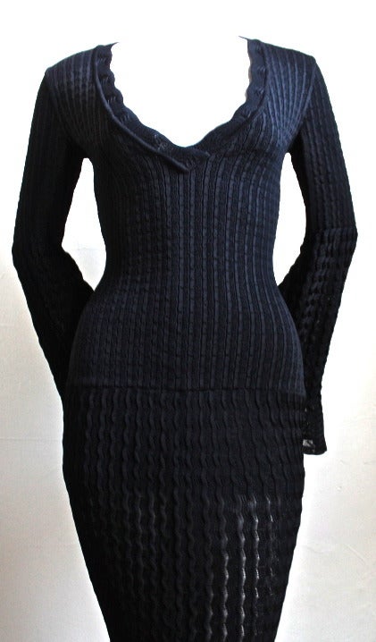 Jet black open knit dress with flounced hemline and bell sleeves from Azzedine Alaia dating to 1992. Dress is labeled a size 'S'. Zips up center back with hidden zipper. Built in shorts. Made in Italy. Excellent condition.