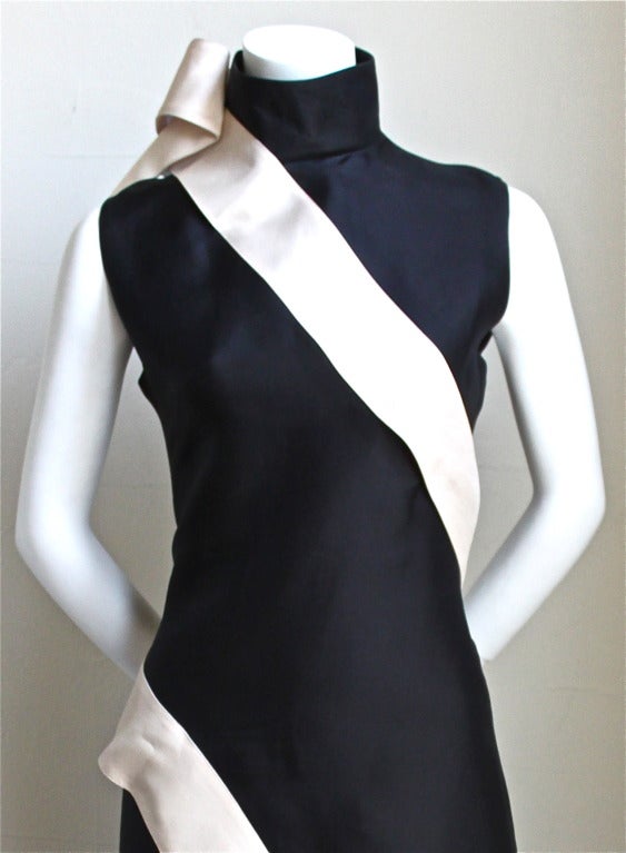 Dramatic black silk gazar dress trimmed in a cream colored sash which wraps entirely around the body. Dress designed by Alexander Mcqueen dating to spring of 2001. Labeled an Italian size 44. Approximate measurements: bust 36
