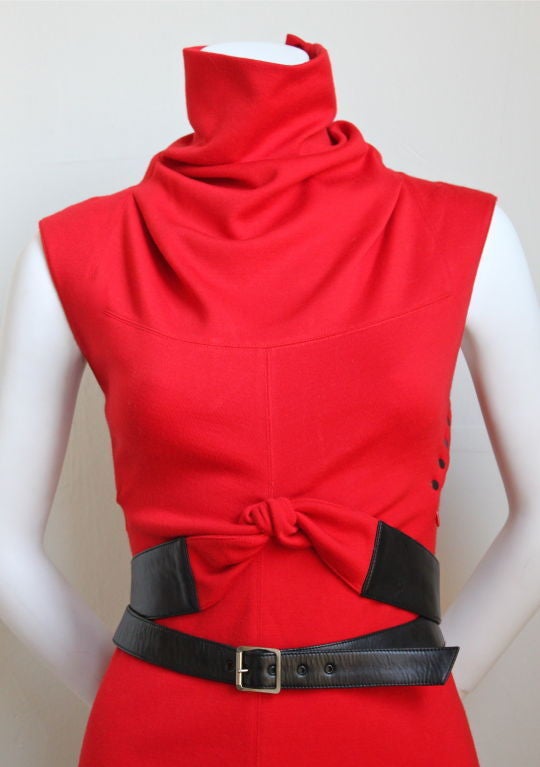 Vivid red, light weight knit jersey mini-dress with unique wrapped black leather belt from Alaia dating to the late 1990's. Labeled a size 'S', although this dress best fits a size XS or S. Dress zips up side and secures with black enameled snaps.