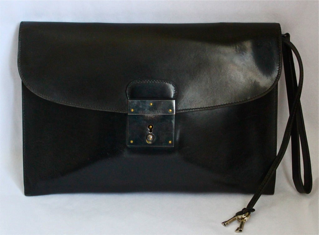 Jet black box leather pouchette with gunmetal hardware including working lock and key made by Hermes dating to the 1980's. Can be used for day or night. Pouchette measures 10