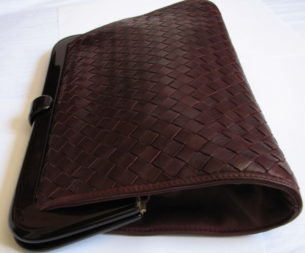 Bottega Veneta burgundy woven leather clutch with lucite frame. One interior zippered pocket. Measures 7.75
